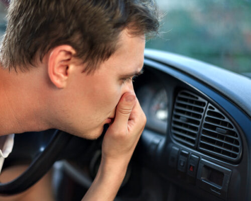 kierowca zatyka nos od brzydkiego zapachu z klimatyzacji